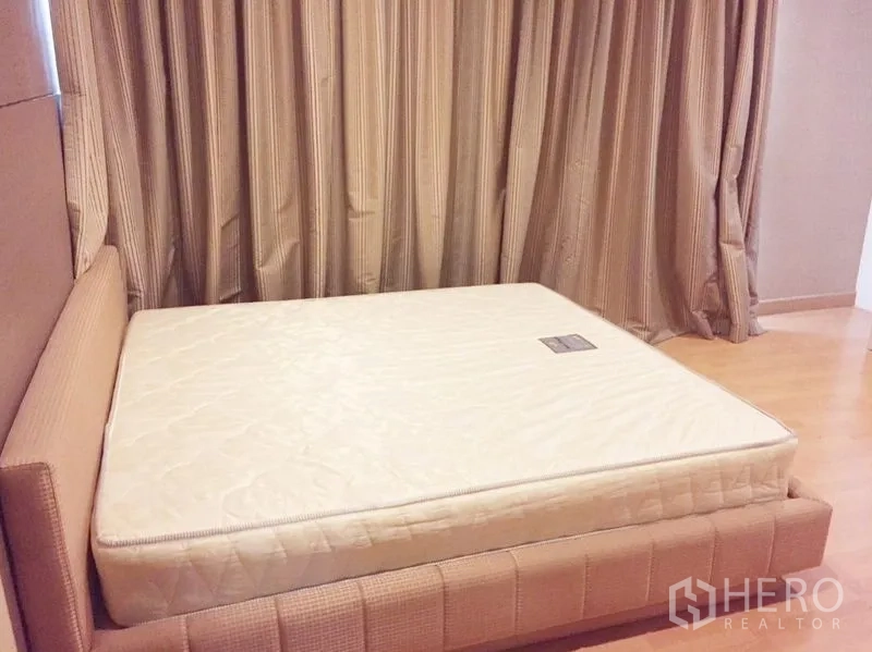 Condominium for rent in Khlong Toei, Bangkok - Second master bedroom with upholstered bed and full-height curtains.