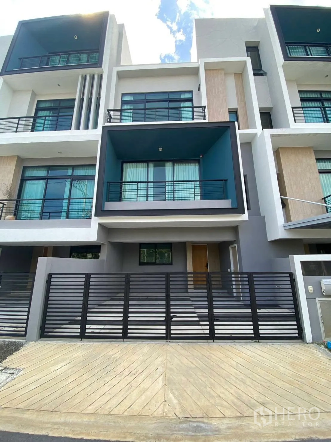 Townhouse for rent in Bang Kapi, Bangkok - Modern three-storey townhouse exterior with recessed balconies and a gated parking area.