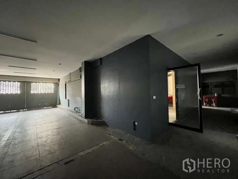 Retail Space for rent in Phaya Thai, Bangkok - Ground-floor open hall with dark feature wall, glass door to utility room and roller shutters.
