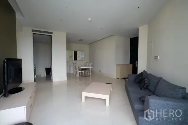 Condominium for rent in Bang Rak, Bangkok - Spacious living room with gray sofa, TV console, light cabinetry and a central coffee table in neutral tones.