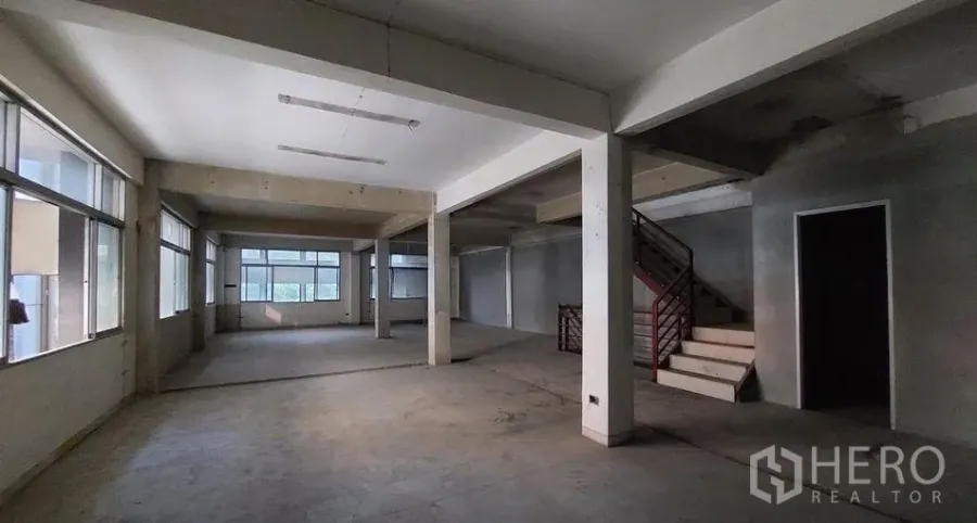 店屋 出租在Watthana, Bangkok - 曼谷艾卡迈商铺开放式室内空间，大窗采光、混凝土地面、结构柱与室内楼梯。