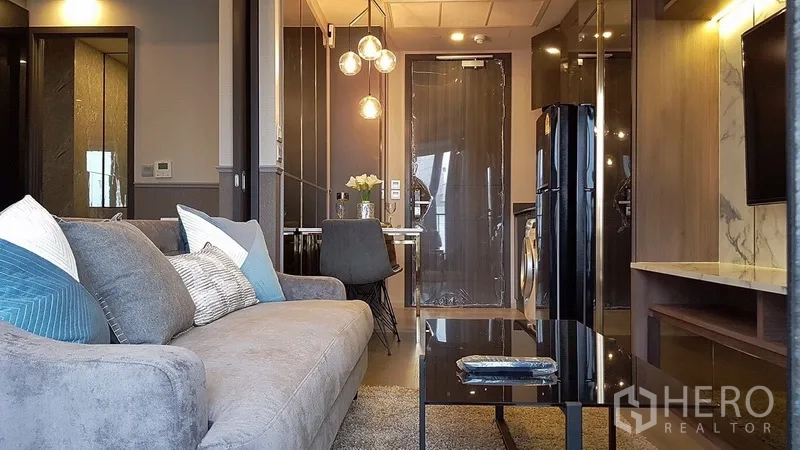 Condominium for rent in Watthana, Bangkok - View from the sofa toward the compact kitchen, dining set and softly lit entryway.