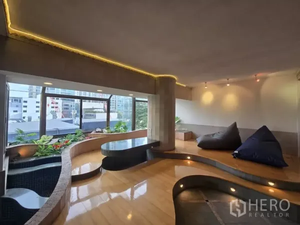 公寓 出租在Pathum Wan, Bangkok - 下沉式休闲区，曲线平台与绿植花槽，落地窗眺望城市。
