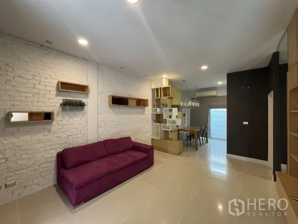 联排别墅 出租在Wang Thonglang, Bangkok - 客厅白色砖墙特色，展示架与餐桌区域。
