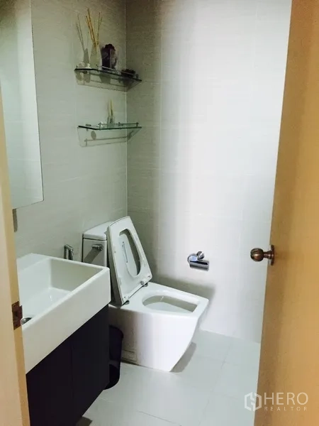 Condominium for rent or sale in Khlong Toei, Bangkok - Guest bathroom with square sink, modern toilet and wall shelves.
