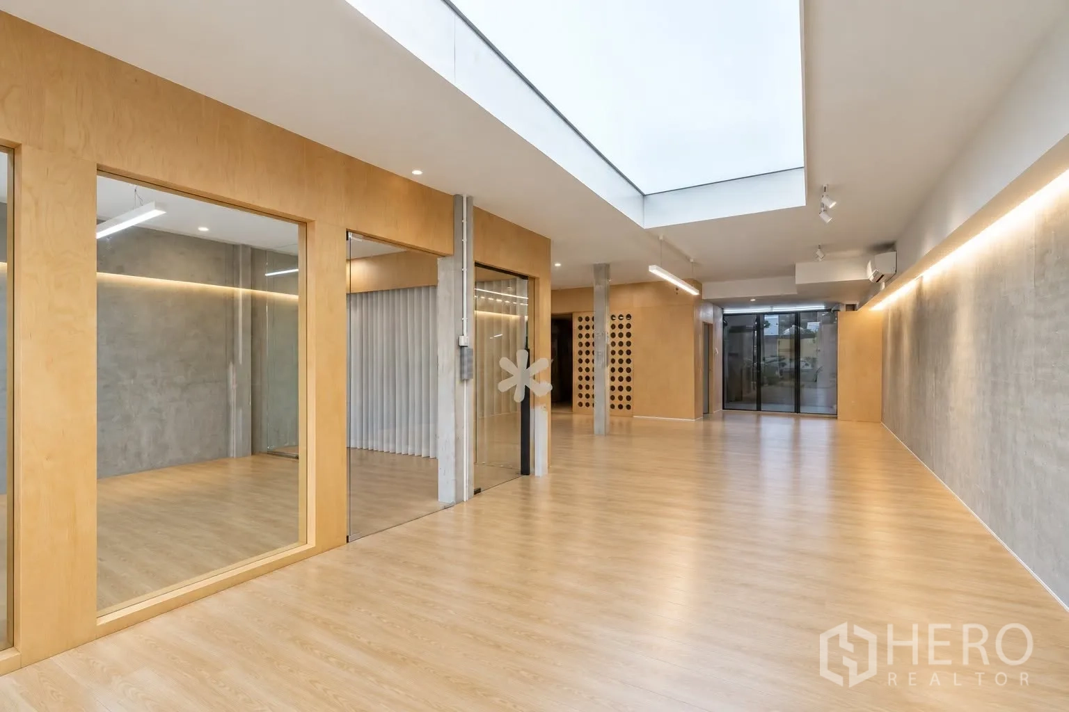 零售空间 for rent in Watthana, Bangkok - 明亮的零售室内，木地板、混凝土墙、天窗与玻璃隔断。