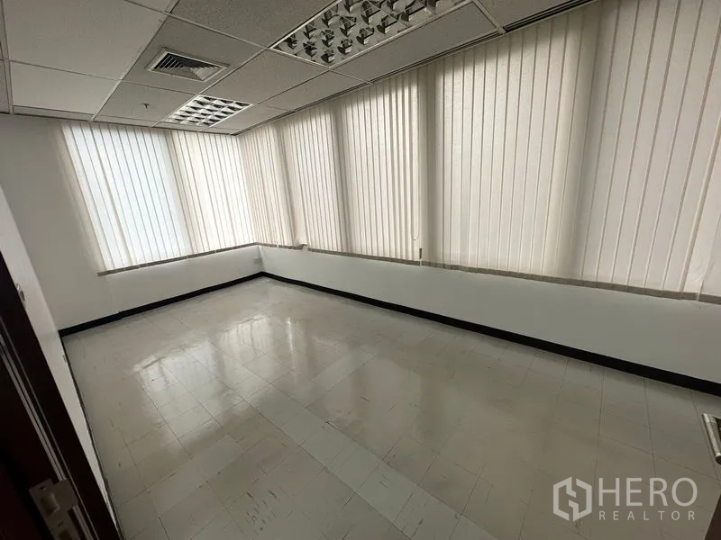 Office Space for rent in Chatuchak, Bangkok - Corner office with wraparound windows and vertical blinds allowing daylight.
