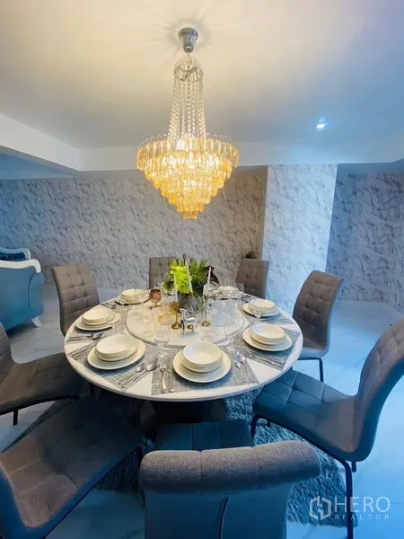 Condominium for rent or sale in Watthana, Bangkok - Round dining table set for eight under a sparkling crystal chandelier.
