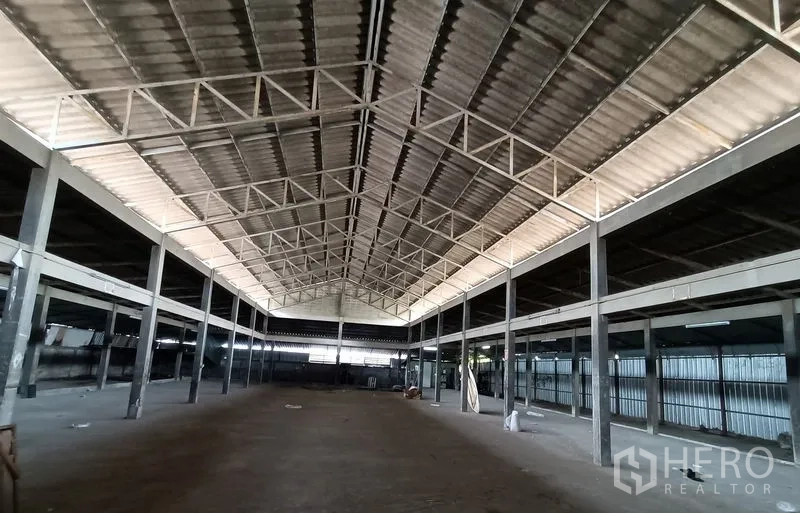 Warehouse for rent in Saphan Sung, Bangkok - Central aisle of empty warehouse under a metal truss roof with clear-span columns.