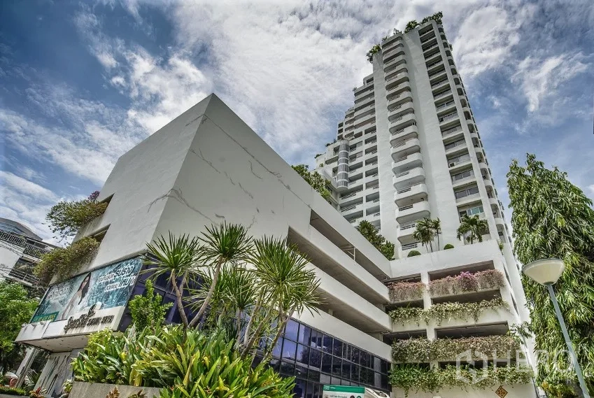 Condominium for rent in Watthana, Bangkok - High-rise facade of Regent on the Park 3 condominium with lush landscaping in Watthana, Bangkok under a blue sky.