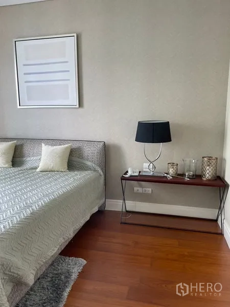 Condominium for rent in Khlong Toei, Bangkok - Bright bedroom with neutral bedding, console table, and wood floors.