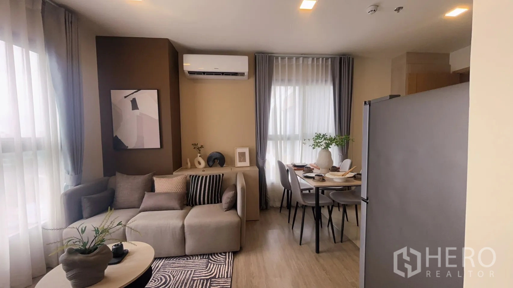 公寓 for rent in Watthana, Bangkok - 室内视角展示沙发、墙面装饰、空调与靠窗餐桌。