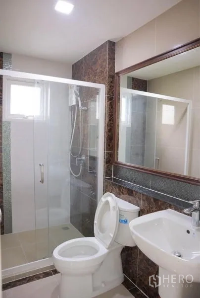Detached House for rent in Bang Phli, Samut Prakan - Modern bathroom with glass shower enclosure, toilet and large mirror.