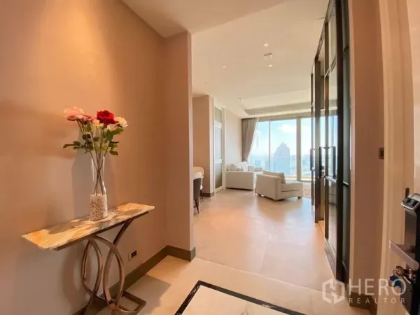 公寓 出租在Khlong San, Bangkok - 明亮的入户走廊，摆放大理石玄关与花瓶，通向落地窗客厅与城市景观。