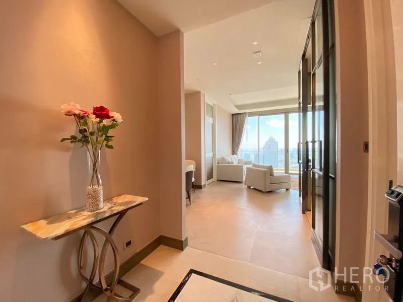 公寓 出租在Khlong San, Bangkok - 明亮的入户走廊，摆放大理石玄关与花瓶，通向落地窗客厅与城市景观。