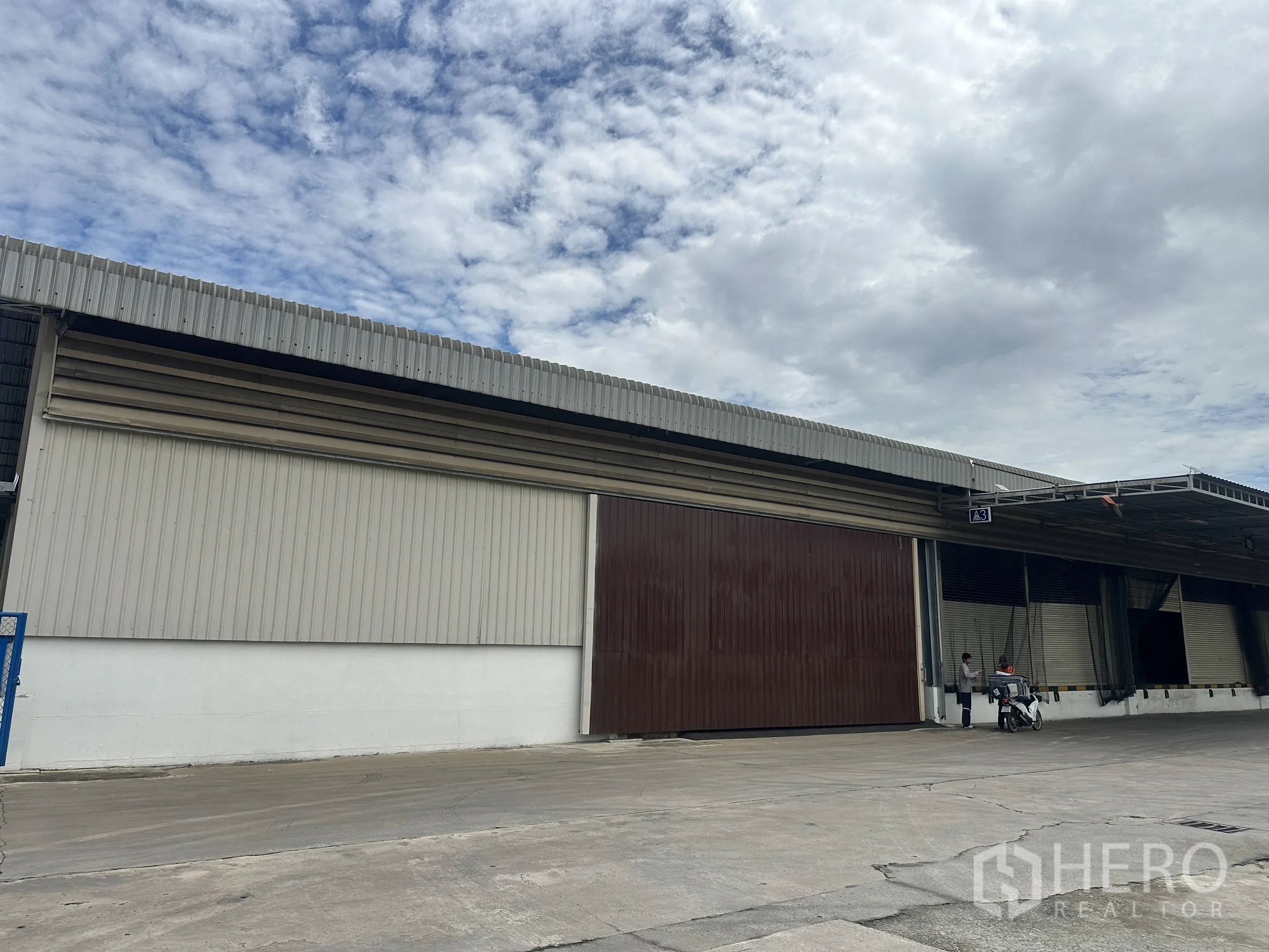 工厂 for rent in Lat Krabang, Bangkok - 金属板外墙工厂侧视，大型棕色滑动门与雨棚清晰可见。