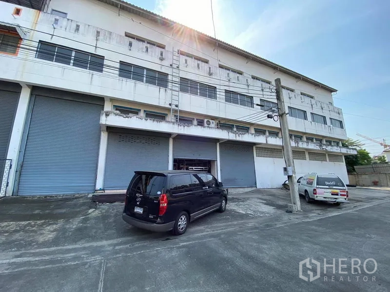 Factory for sale in Bang Phli, Samut Prakan - Multi-bay factory exterior in Bang Phli with roller shutter doors and on-site parking.