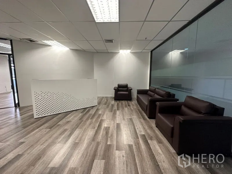 Office Space for rent or sale in Din Daeng, Bangkok - Reception area with white counter and dark sofas next to a glass wall.
