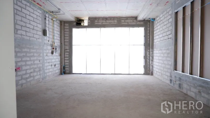 Retail Space for rent in Khlong Toei, Bangkok - Open-plan concrete retail unit with ceiling conduits and a bright window wall near BTS Phrom Phong.