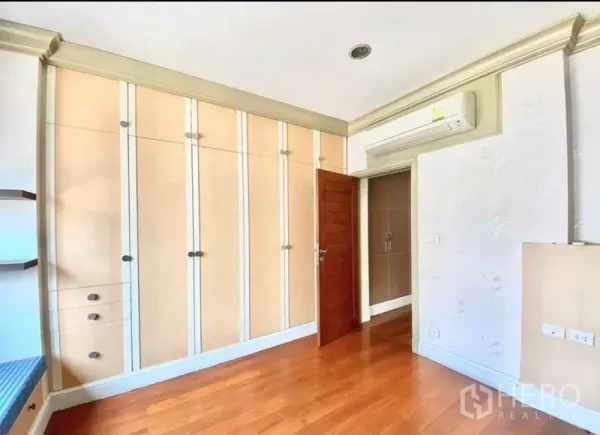Home Office for rent in Pak Kret, Nonthaburi - Bedroom with wall-to-wall wardrobes, wood flooring and air-conditioning unit.