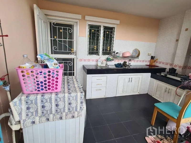 Detached House for rent in Sai Mai, Bangkok - Outdoor Thai kitchen and laundry zone with black countertops and white cabinets.