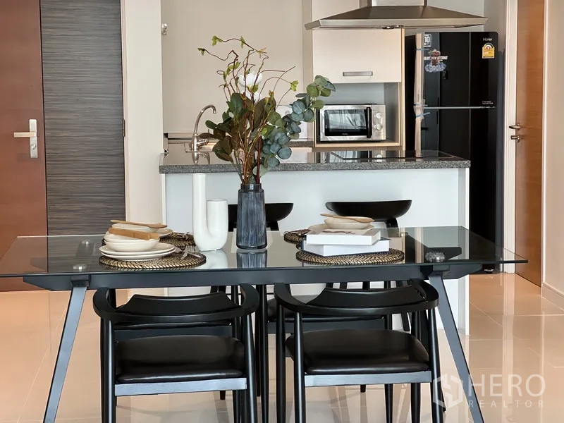 Condominium for rent in Watthana, Bangkok - Close-up of set dining table facing kitchen island with microwave and fridge.
