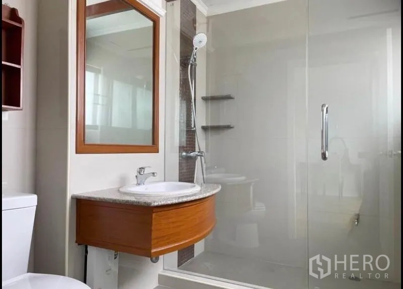 Condominium for rent in Sathon, Bangkok - Modern bathroom with glass-enclosed shower, wooden vanity and large mirror.