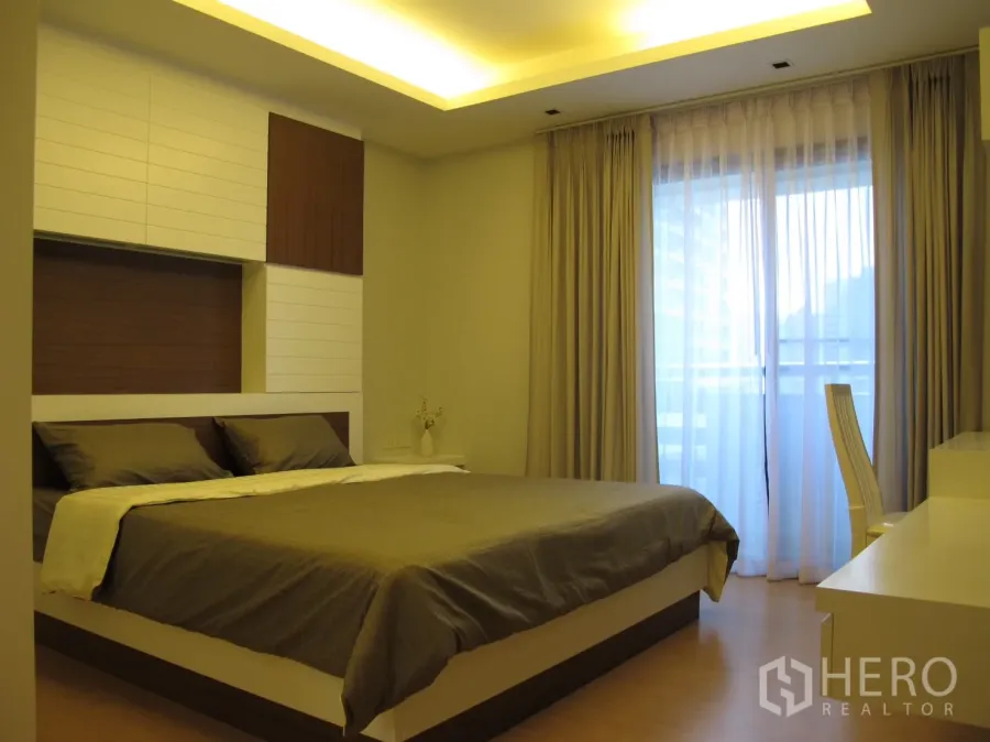 คอนโด ให้เช่าในWatthana, Bangkok - ห้องนอนหลักโทนอบอุ่น เตียงแพลตฟอร์ม ไฟซ่อน และผ้าม่านติดระเบียง