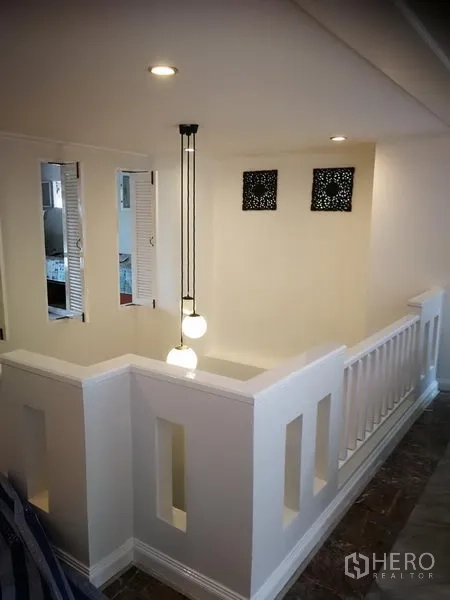 Townhouse for rent or sale in Watthana, Bangkok - Stair landing with white balustrade and modern pendant lighting.
