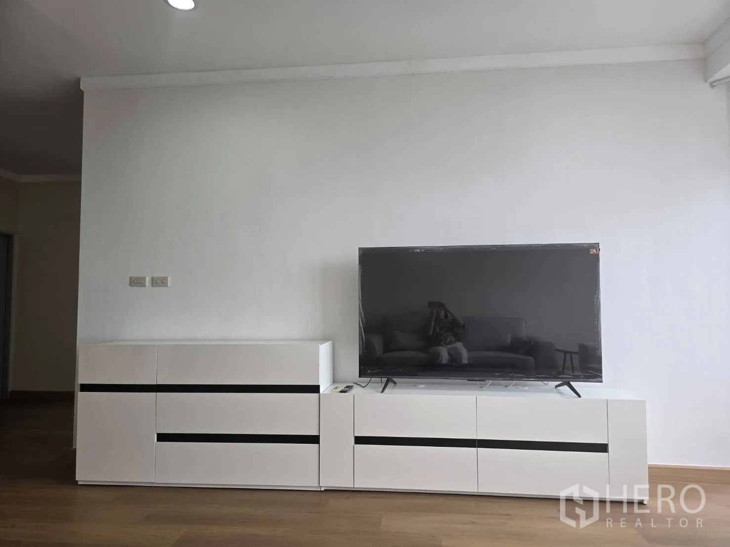 Condominium for rent in Khlong Toei, Bangkok - Large flat-screen TV on sleek white cabinet against a minimal wall.