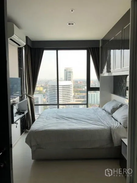 Condominium for rent in Khlong Toei, Bangkok - Master bedroom facing floor-to-ceiling windows with city view and TV cabinet.