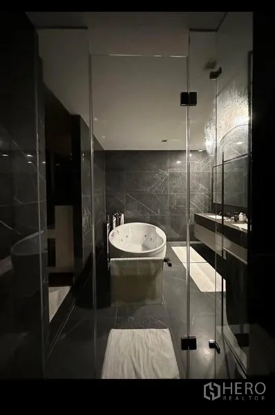 Detached House for rent - Contemporary bathroom with dark stone tiles, glass partitions and a freestanding soaking tub.