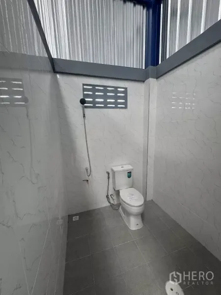 货栈 出租在Bang Phli, Samut Prakan - 干净的瓷砖卫生间，坐便器、手持喷枪与地漏。