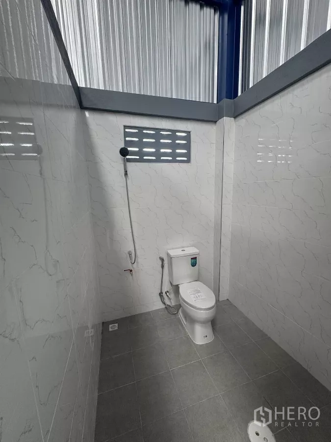货栈 出租在Bang Phli, Samut Prakan - 干净的瓷砖卫生间，坐便器、手持喷枪与地漏。