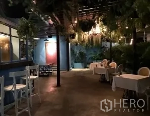 零售空间 出租在Watthana, Bangkok - 夜间庭院露台，悬挂绿植与串灯，小餐桌