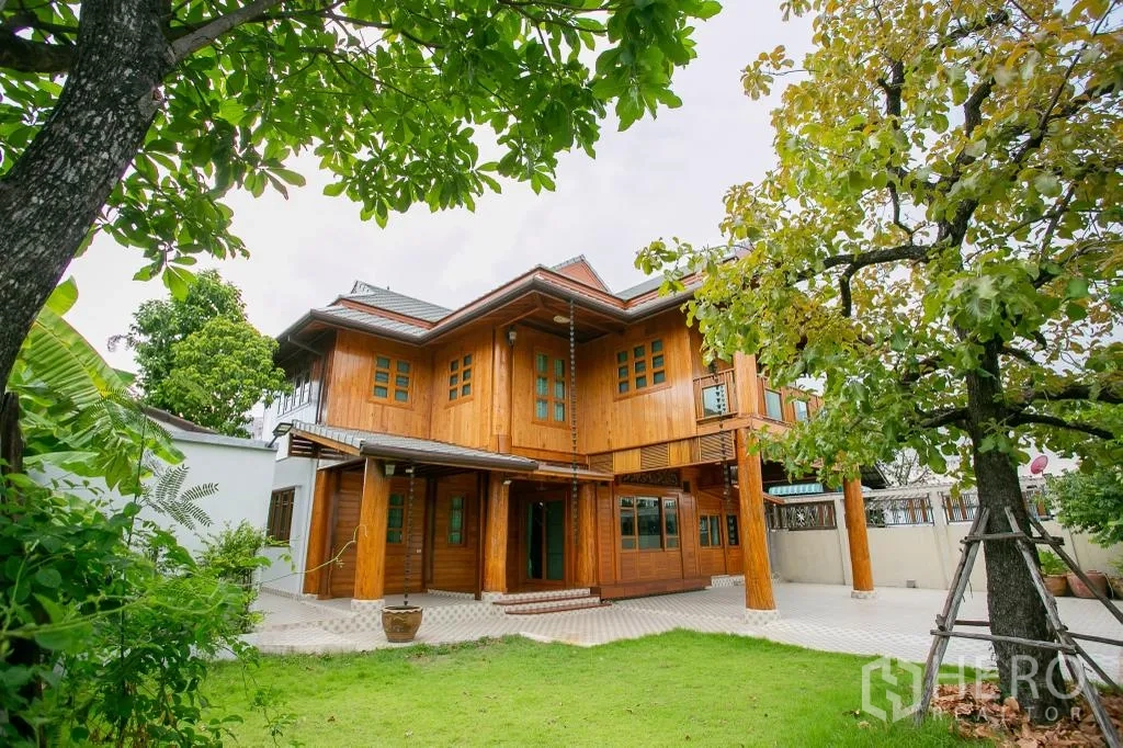 独栋房屋 for rent or sale in Huai Khwang, Bangkok - 庭院正面观两层木屋，配草坪与树木。