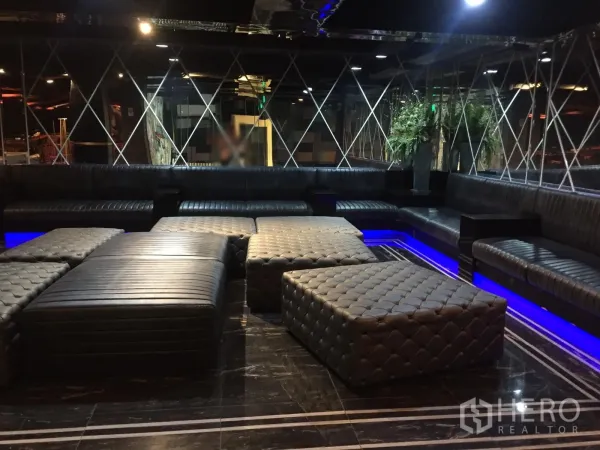 Retail Space for rent in Watthana, Bangkok - Dimly lit lounge with black leather banquettes, tufted ottomans and blue LED accents.