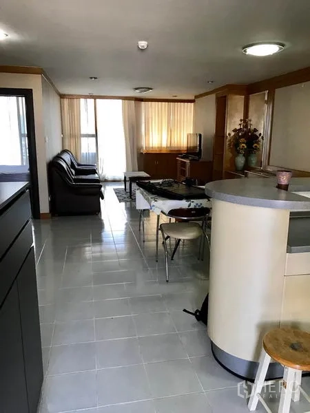 Condominium for rent in Watthana, Bangkok - Open-plan living and dining area with leather sofa, TV unit, tile floors and large curtained windows in a Sukhumvit condo.