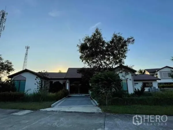 Warehouse for sale in Chon Buri - Single-storey office or residence building with driveway and mature trees at dusk.