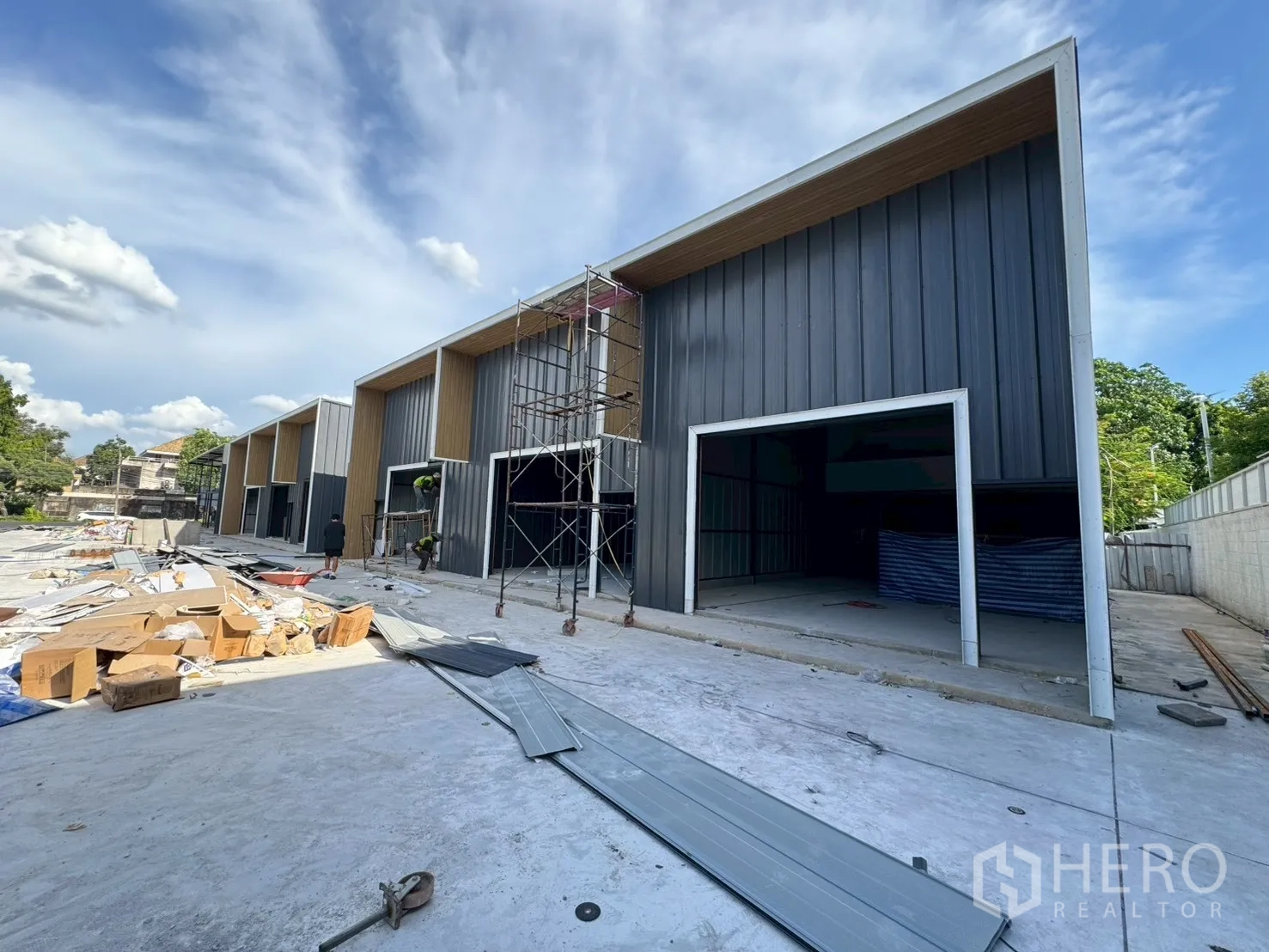 Warehouse for rent in Wang Thonglang, Bangkok - New warehouse units under construction with tall openings, scaffolding and materials on the ground.