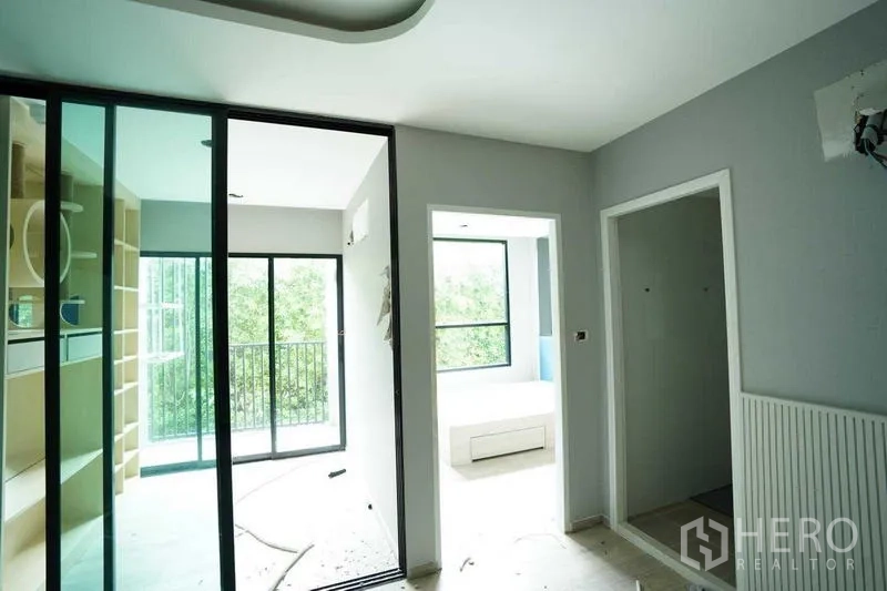 Standalone for rent in Bang Na, Bangkok - Hallway with glass sliding doors opening to a small balcony and adjacent rooms.