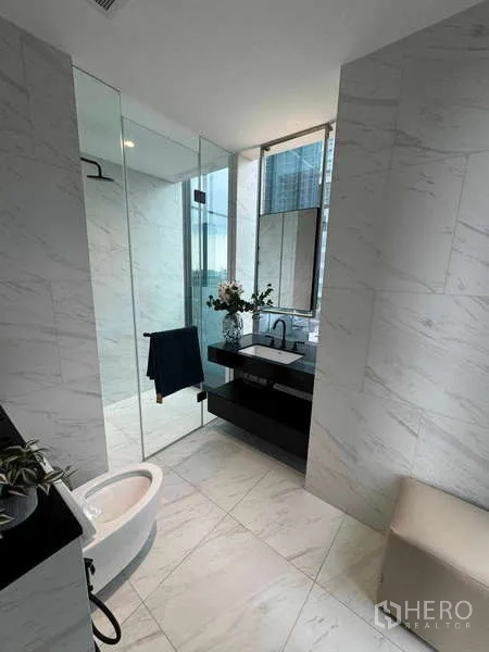 Condominium for rent in Bang Rak, Bangkok - Bright marble bathroom with glass shower, vanity and a window to city views