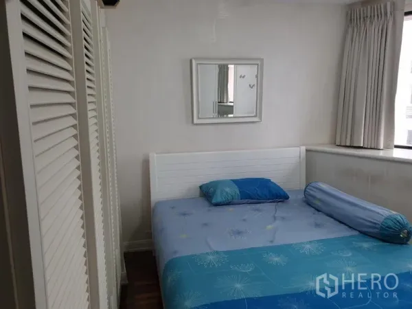 Condominium for rent in Khlong Toei, Bangkok - Guest bedroom with window light, white panel bed, blue bedding and louvered closets.