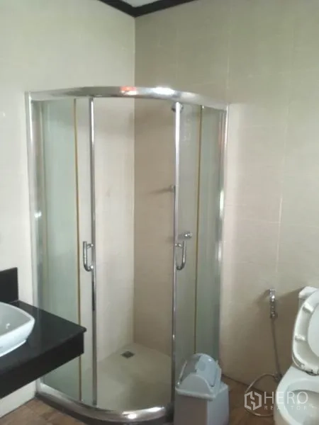 Townhouse for rent in Din Daeng, Bangkok - Bathroom with glass-enclosed corner shower and vanity.