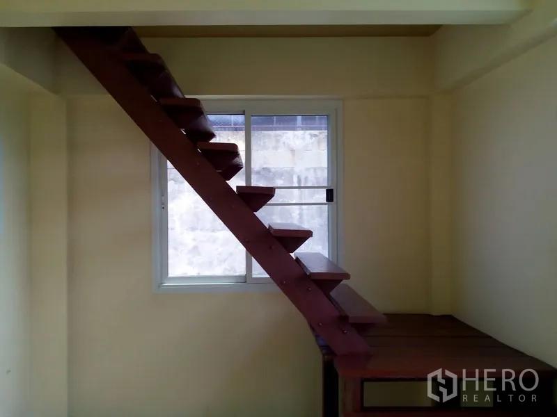 Shophouse for rent in Phra Khanong, Bangkok - Side profile of open-riser stairs next to a sliding window.