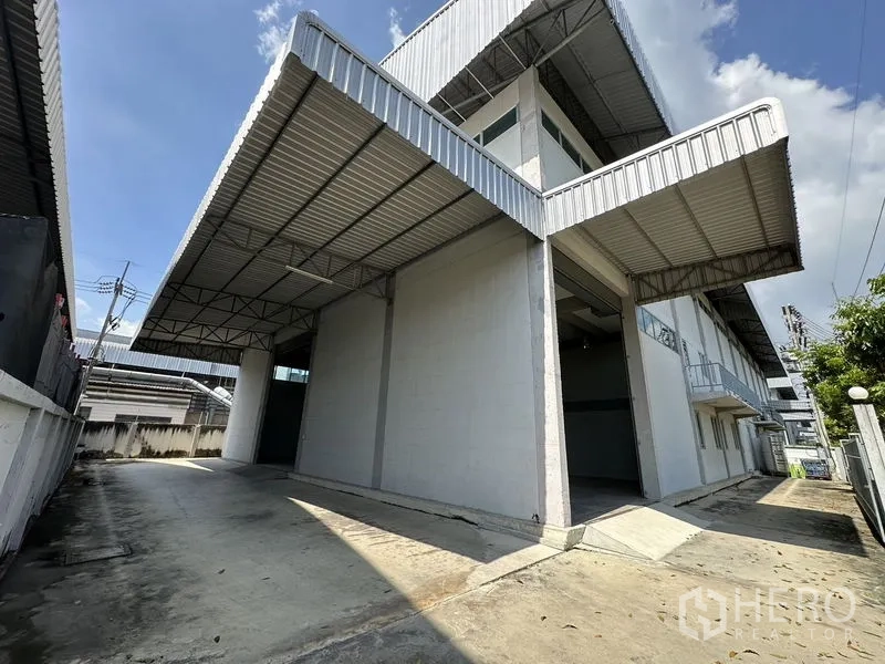 Factory for rent in Lam Luk Ka, Pathum Thani - Covered loading bays and side access road wrapping around the factory building.