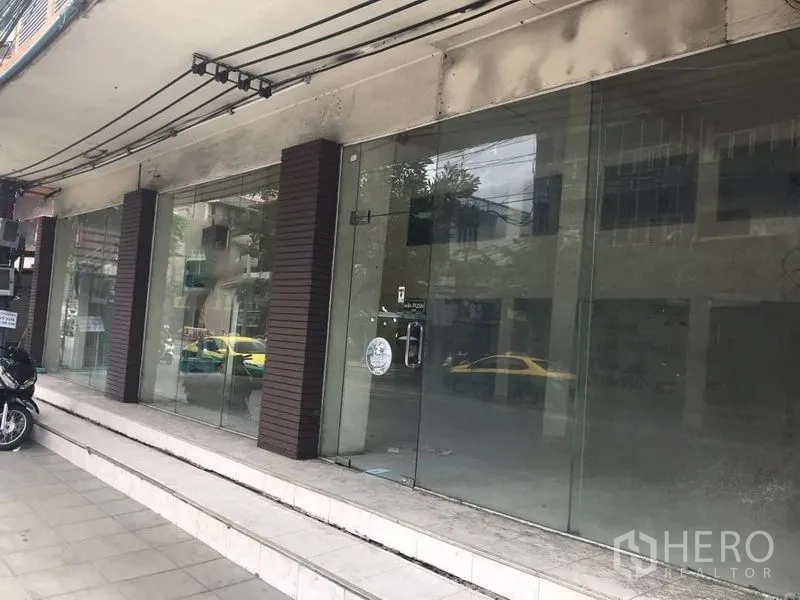 店屋 出租在Watthana, Bangkok - 多扇玻璃门店面，台阶从人行道通向入口。