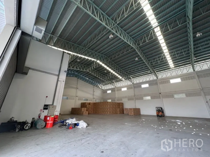 Warehouse for rent in Lat Krabang, Bangkok - Spacious warehouse interior with high steel truss roof, skylight strips, and open floor space for storage.