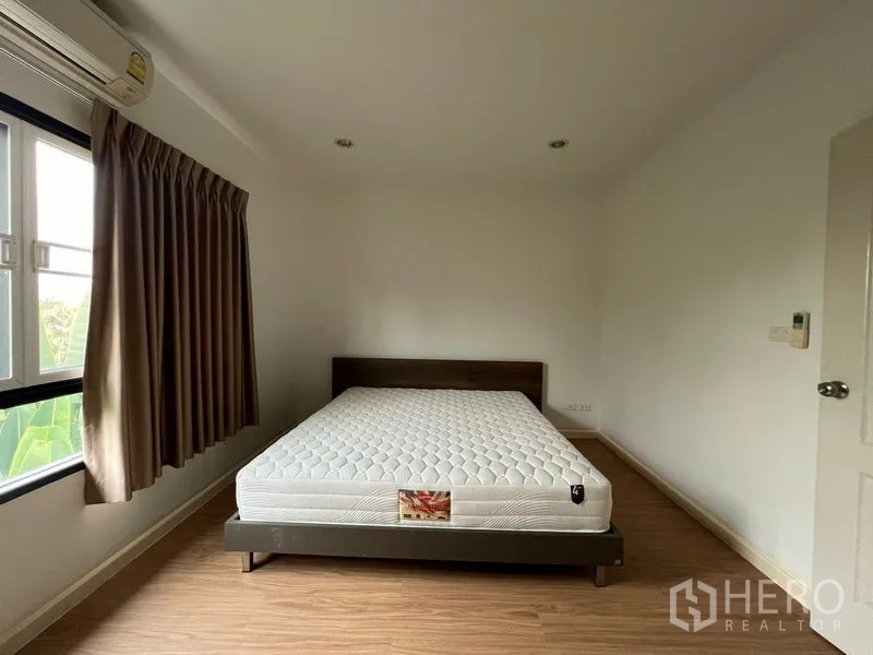 Townhouse for rent in Bang Kapi, Bangkok - Secondary bedroom with large window, brown curtains and double bed.