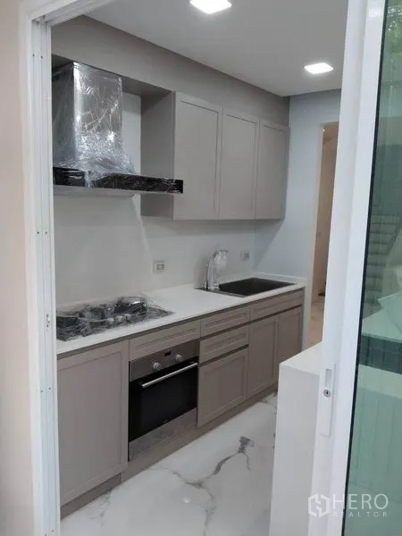 Townhouse for rent in Yan Nawa, Bangkok - Galley kitchen with built‑in appliances and sliding glass door.